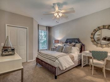 Furnished model bedroom area with bed and desk and desk chair
